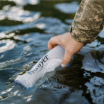 Військовий набирає воду у м’яку пляшку Sawyer Squeeze Bottle з природної водойми