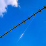 Колючий дріт комплексу Шипшина із захопленою оптоволоконною ниткою FPV-дрона на тлі неба